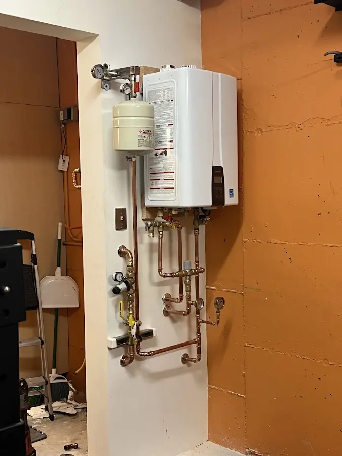 Plumbing technician inspecting water heater connections in Madisonville